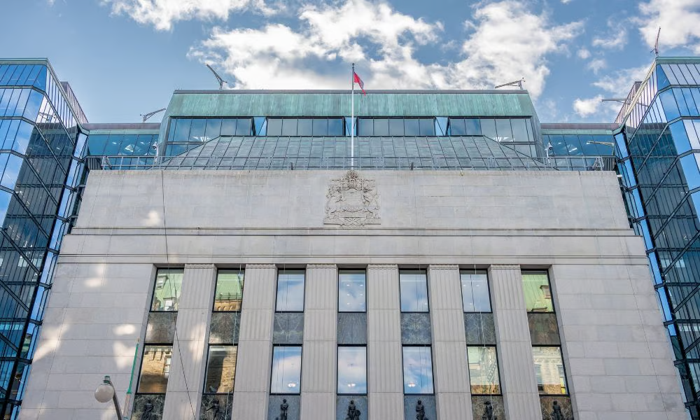 Stone and glass government building with a Canadian flag, representing Canada’s central banking and financial system