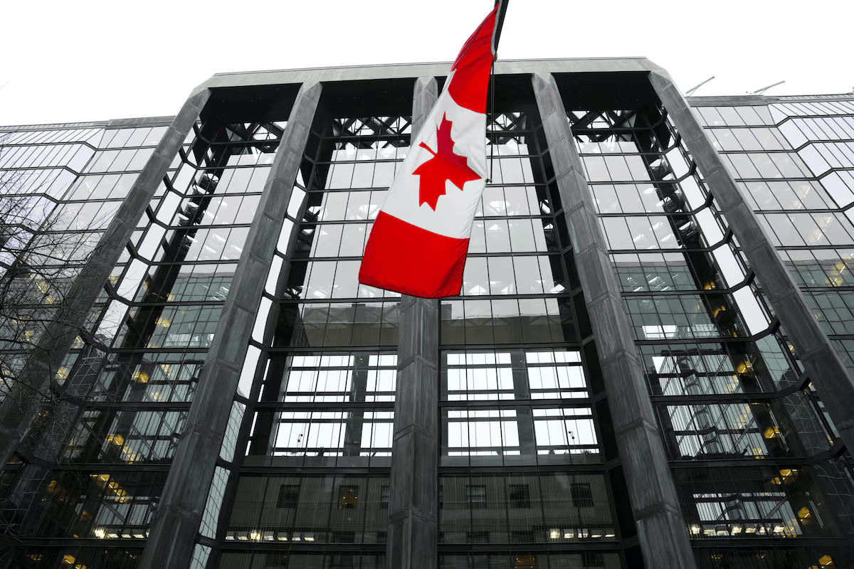 Canadian flag flying in front of a modern glass building, symbolizing Canada’s financial and regulatory institutions